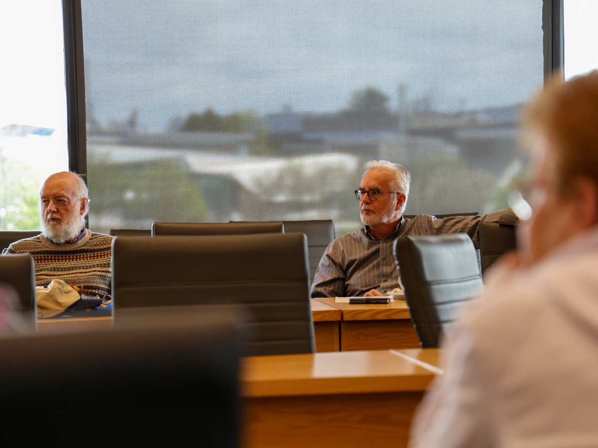 Three people sitting around a boardroom table