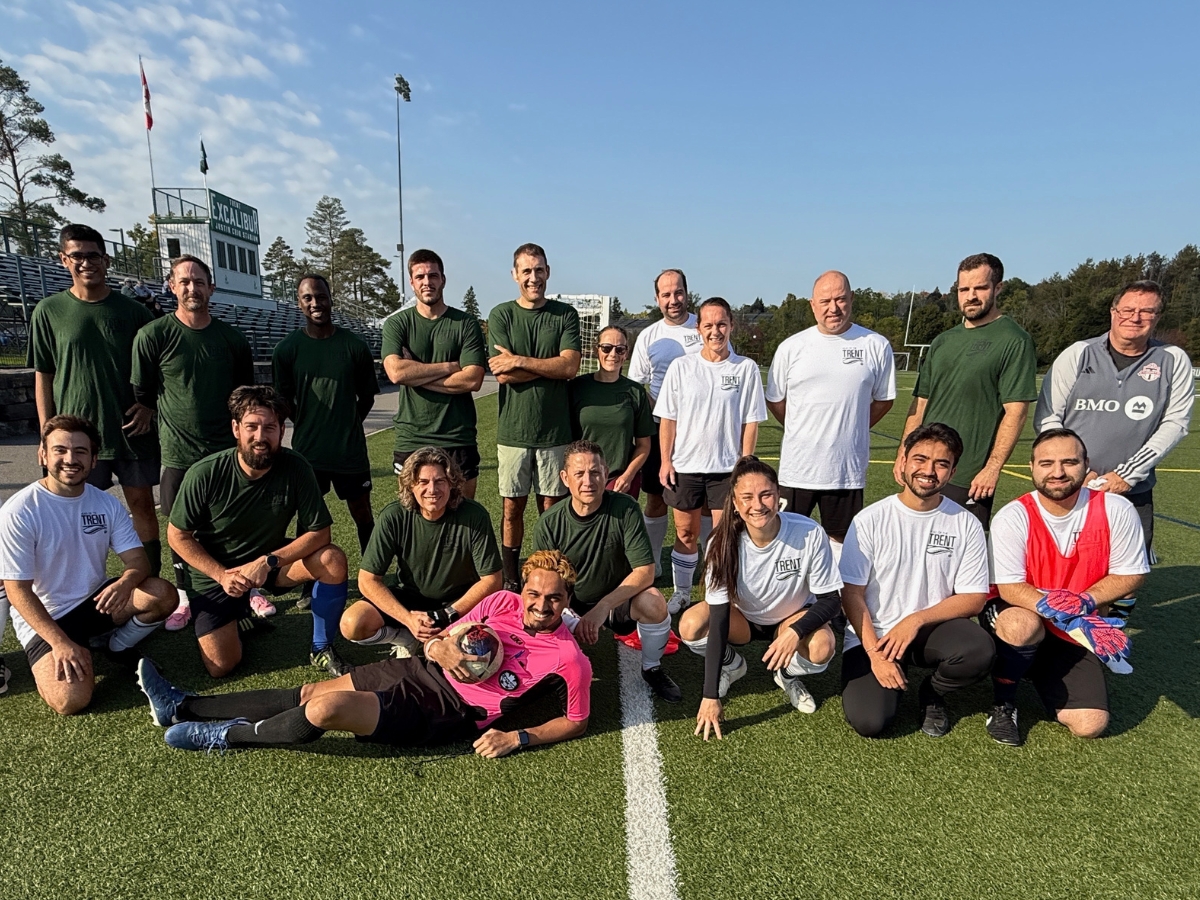 A group of people on the soccer field, smiling at the camera