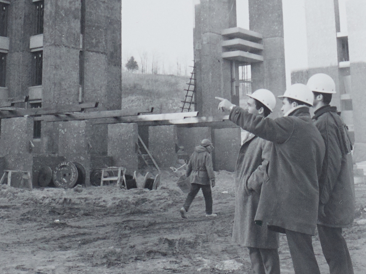 A black and white photo of construction workers outside, pointing