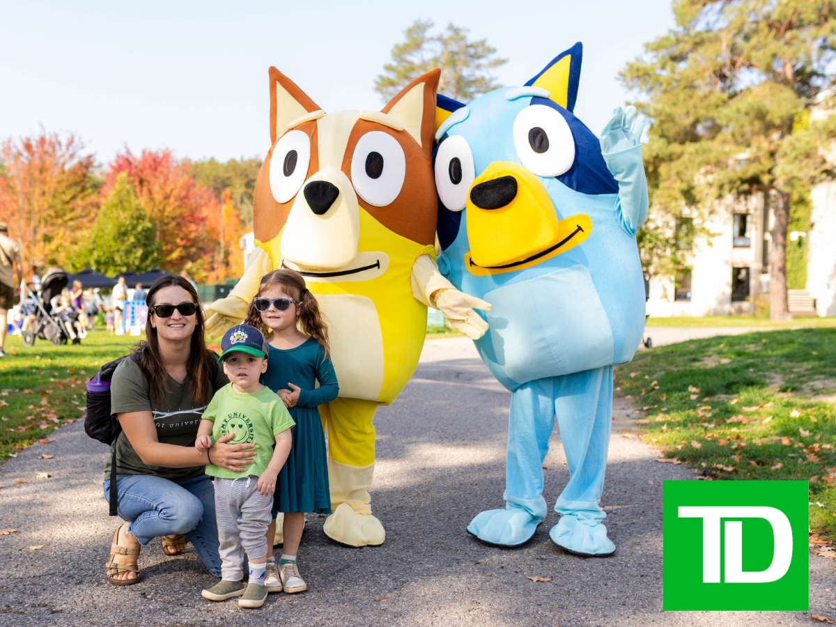 A woman and two children posing with two dog mascots