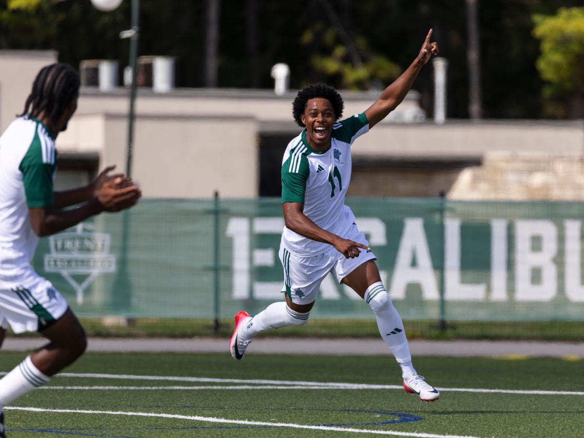 A soccer playing celebrating a goal with his hands in the air