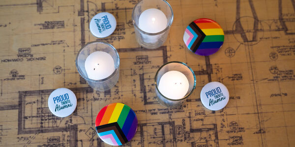 Collection of items on a table including tealight candles, Proud Trent U alumni buttons, and Pride Flag buttons