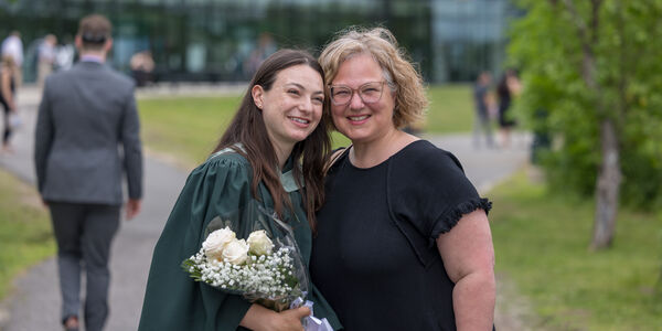 2 women smiling, one in graduation regalia
