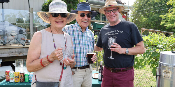 Three people in a backyard garden smiling at the camera