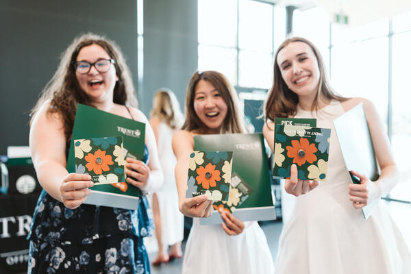 3 girls smiling, holding brochures