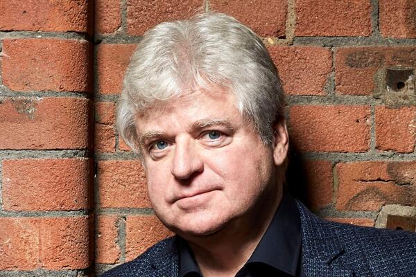 Linwood Barclay in front of an exposed brick wall