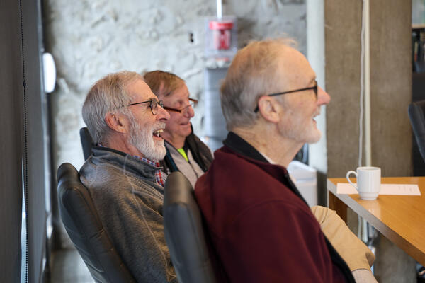 Three men seated at a meeting.