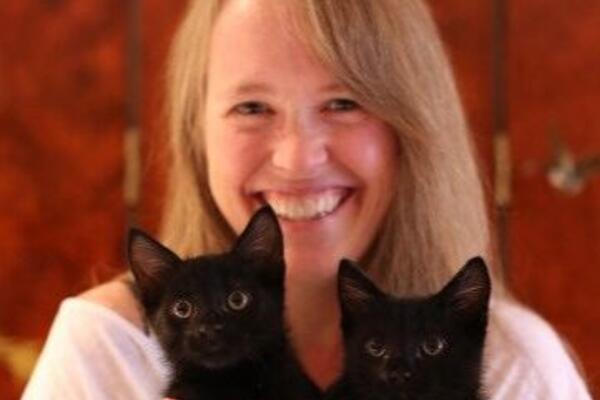 Woman holding up two black kittens