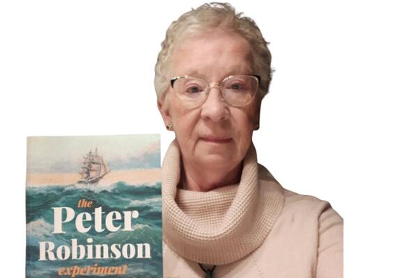 Mary English-Cooper holding up her book The Peter Robinson Experiment