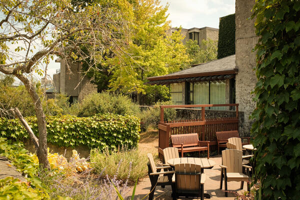 Alumni House Tony Storey courtyard in the summer, lush green trees and ivy surround patio furniture