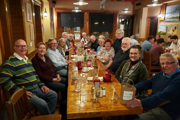 A group of people in a pub around a table smiling at the camera