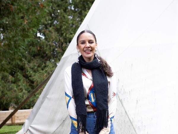 Sandra Lamouche standing infront of a tipi holding red hoops