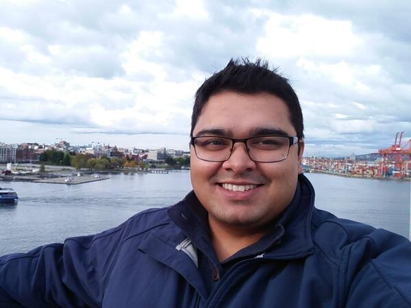 Photo of person smiling while standing in front of a river.
