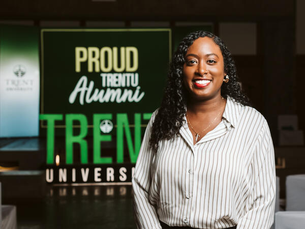 Alumni standing infront of Proud TrentU alumni sign