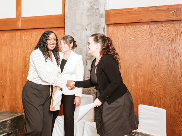 Women receiving award, shaking hands with award announcer
