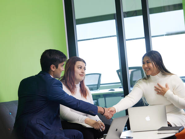 3 people in meeting, 2 shaking hands