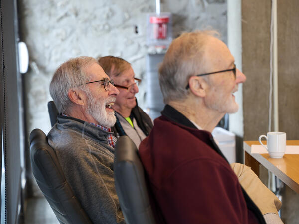 3 men sitting in a conference room smiling
