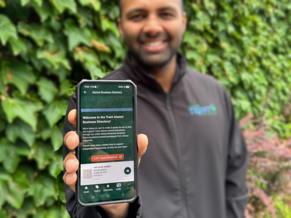 Man smiling holding phone up on Business Directory, photo focused on phone
