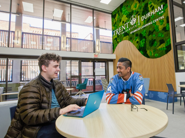 Two people sitting at a table working on a laptop
