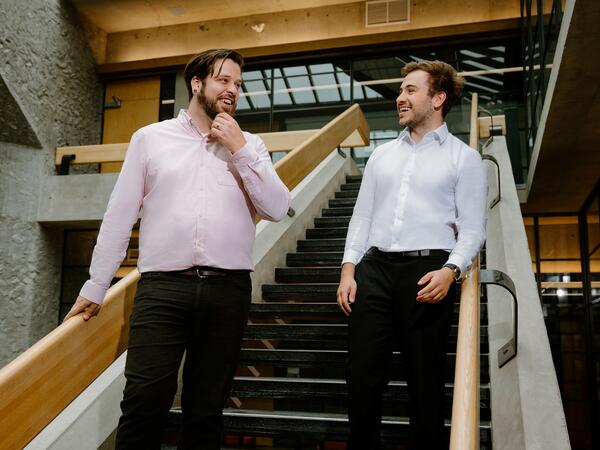 2 men in business attire walking down stairs talking