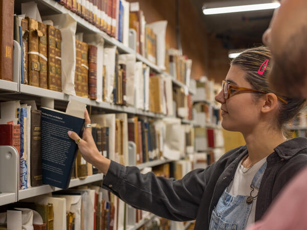 People selecting a book from a library bookshelf