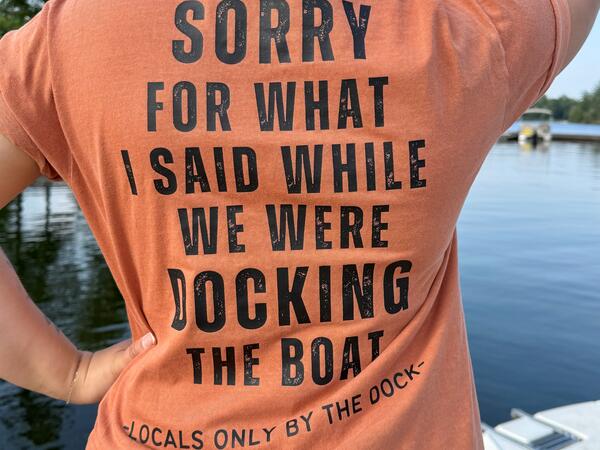 A woman facing away from the camera wearing a t-shirt that says "Sorry for what I said while we were docking the boat" on the back