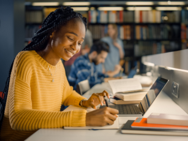 Woman sitting at desk with laptop, taking notes.