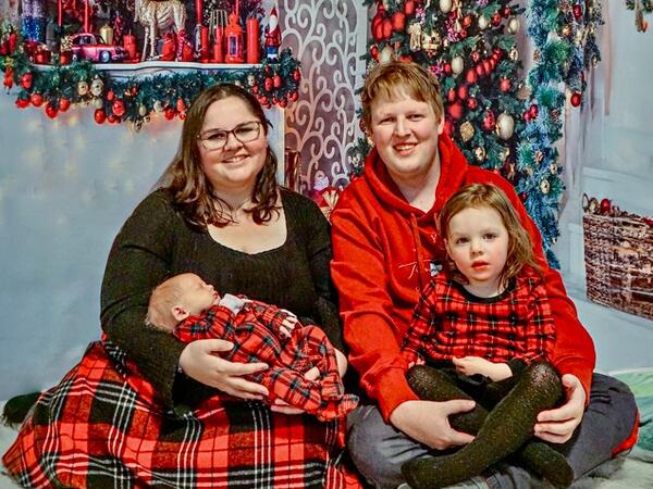A family of four in a winter scene, smiling at the camera