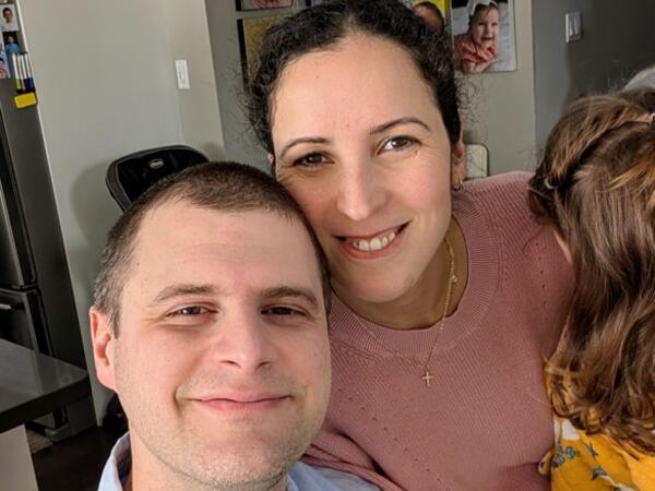 A couple holding a child, smiling at the camera