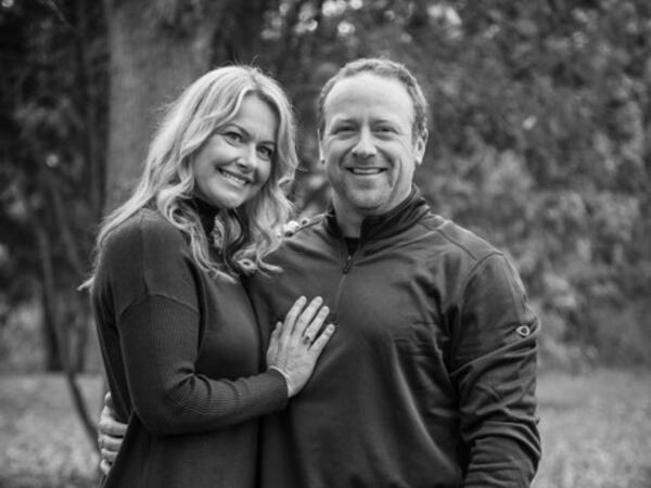 A couple outside posing, smiling at the camera