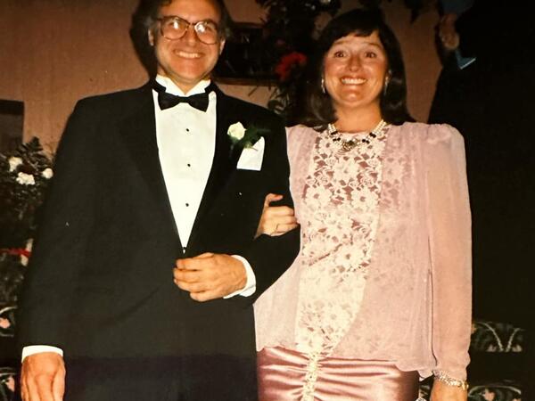 Couple standing on staircase, smiling at the camera in formal clothing