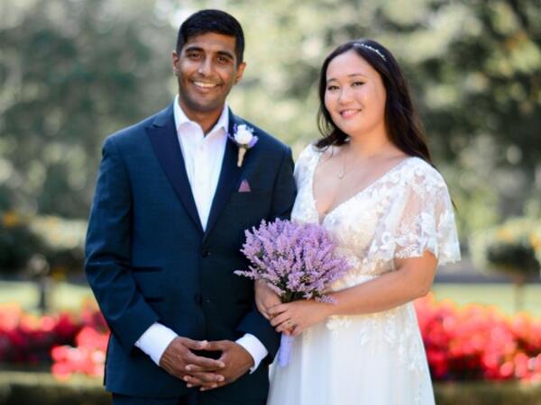 A couple on their wedding day standing outside smiling at the camera