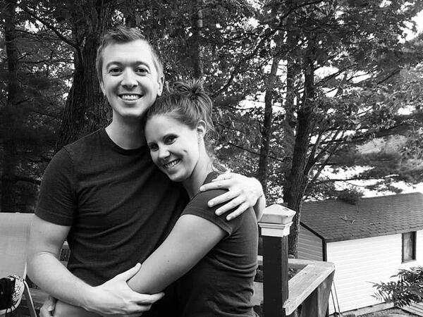 A black and white photo of a couple hugging, smiling at the camera