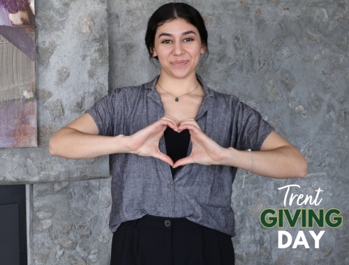 A Trent student smiles while making a heart shape with her hands
