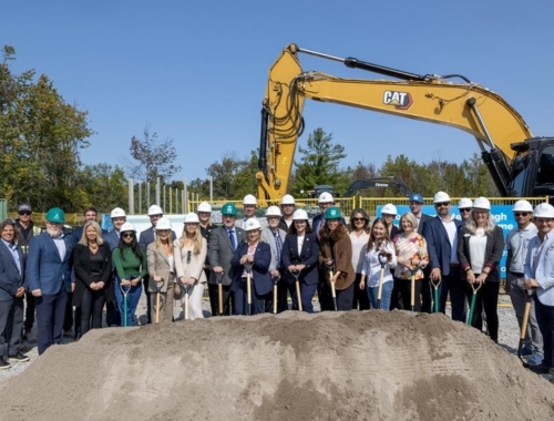 A group wearing hardhats stands in front of a tractor during the groundbreaking ceremony.