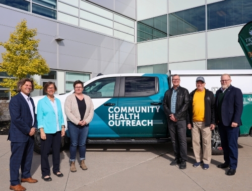 People standing in front of Community Health Outreach vehicle
