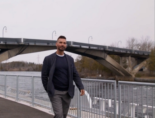Todd Anthony Tyler walks on campus with the Faryon Bridge in the background