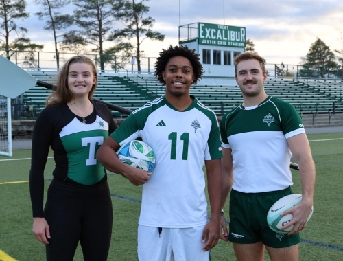 Three student-athletes standing outside on the field at Trent University