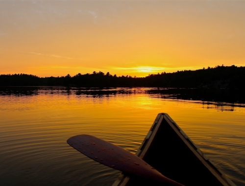 A canoe on a still lake with a sunset