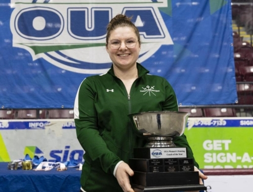 A woman smiling, holding a trophy 