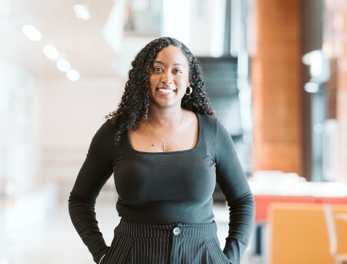 Woman smiling at the camera with her hands in her pockets