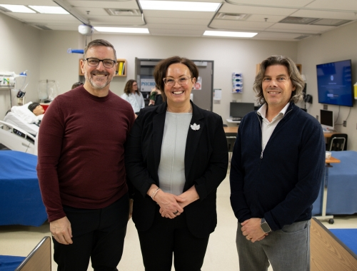 Three people standing in a nursing lab at Trent looking at the camera