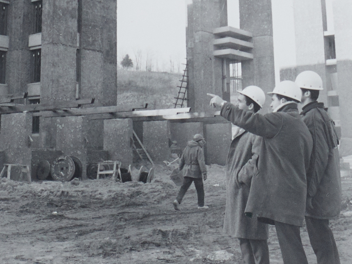 A black and white photo of construction workers outside, pointing