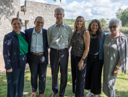 A group of six people standing shoulder to shoulder outside