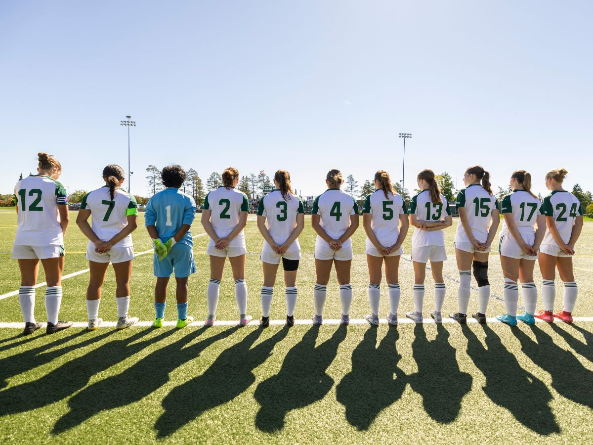 Soccer players lined up on the field, with their backs facing the camera
