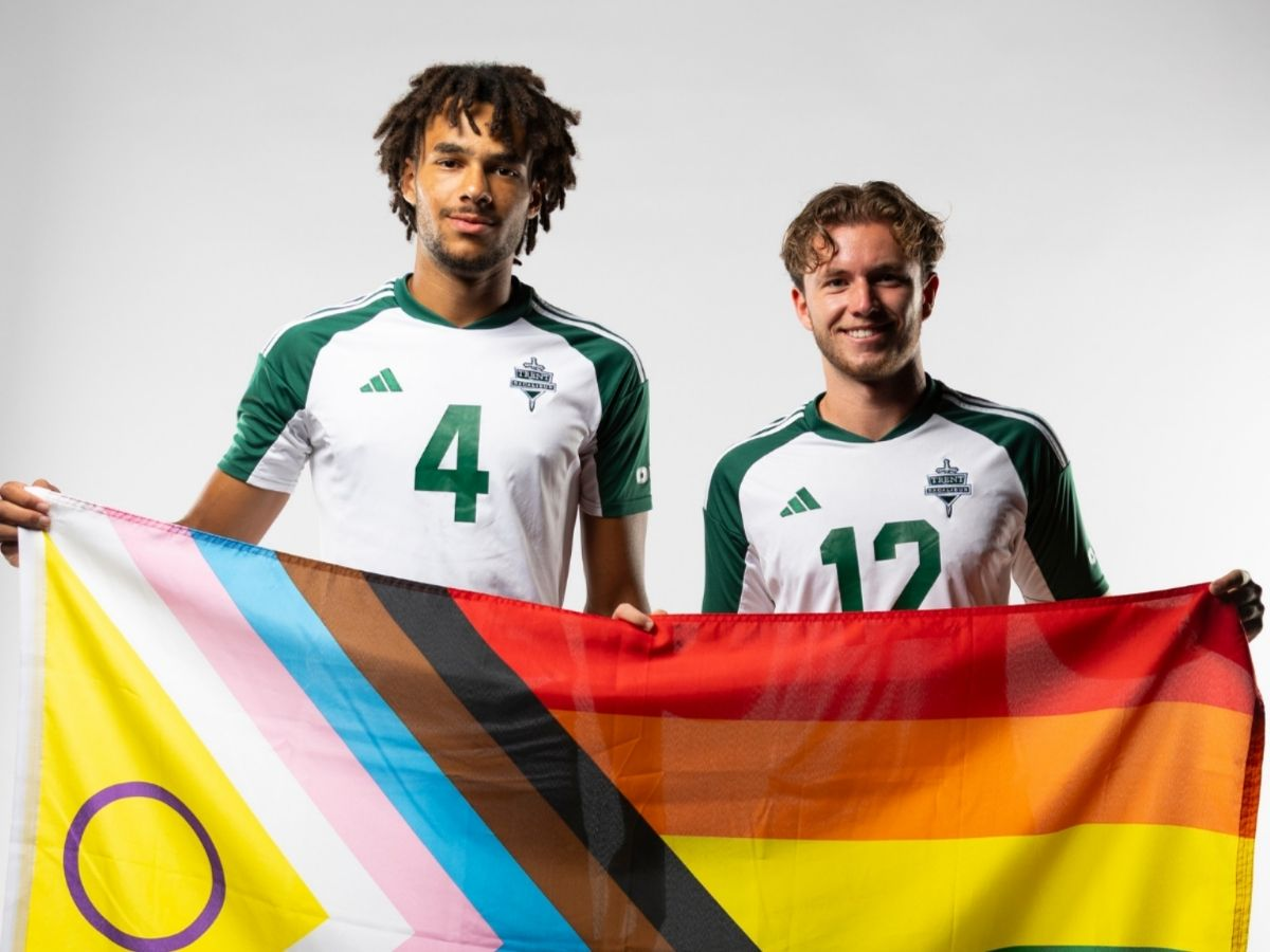 Two mens soccer players holding pride flag