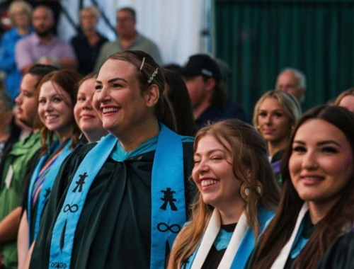 Students at a convocation ceremony, smiling with their convocation gowns on