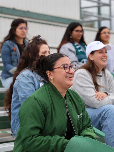 A photo of five people in the stands cheering on a sports team