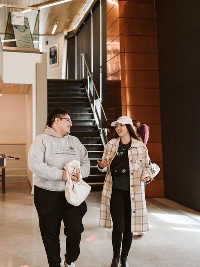 2 people walking and smiling, dressed for cold weather