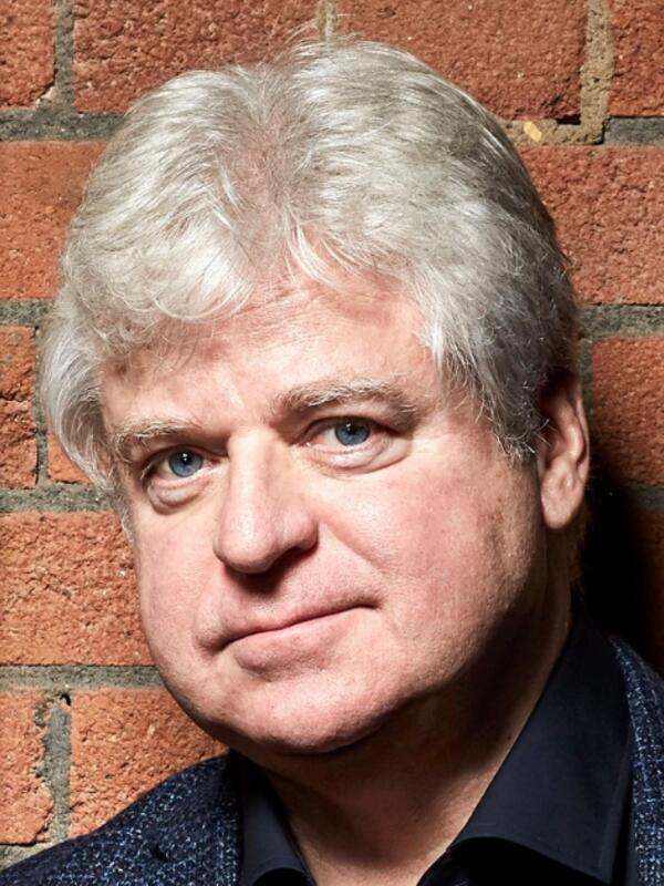 Linwood Barclay in front of an exposed brick wall